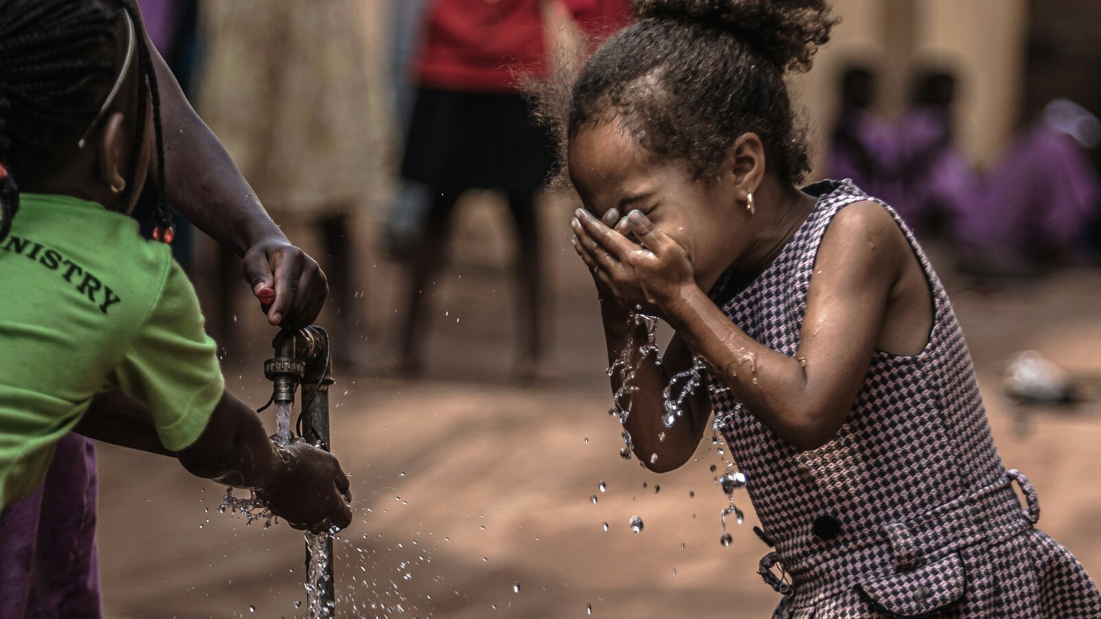 A child fills a container at a hand pump well in a rural village