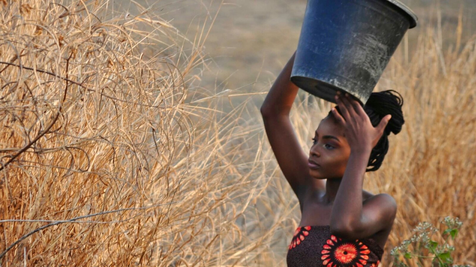Women carrying water containers home from a village well